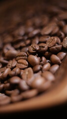 vertical close-up photo of coffee beans in the dark with bokeh and out of focus in the foreground