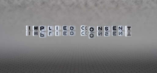 implied consent word or concept represented by black and white letter cubes on a grey horizon...