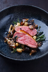Barbecue gourmet duck breast filet with skin served with mushrooms and truffle cream as close-up on...