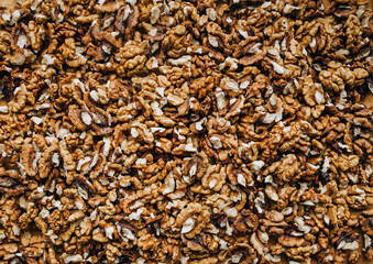 Background, texture of many brown pieces of walnuts, peeled nuts lying on the table. Food photography, top view.