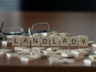 landlady word or concept represented by wooden letter tiles on a wooden table with glasses and a book - obrazy, fototapety, plakaty