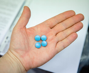 A blue pill in the man's hand.