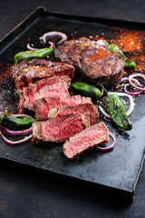 Traditional barbecue dry aged wagyu rib-eye beef steaks served with paprika and onion rings as close-up on an old rustic metal tray