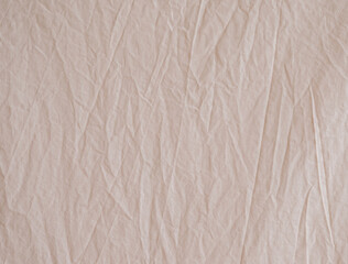 Carelessly crumpled beige fabric as a background image. Uneven surface. The texture of the cotton fabric.