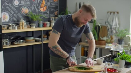 Food blogger chopping fresh cilantro at kitchen table, smiling and speaking on camera while giving online cooking class