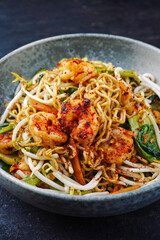 Modern style traditional stir-fried Thai phak kung with king prawns, vegetable and noodles served as close-up in a Nordic design bowl