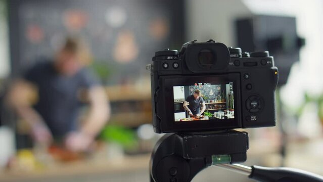 Close up selective focus shot of professional camera filming video of food blogger cooking in kitchen and telling recipe