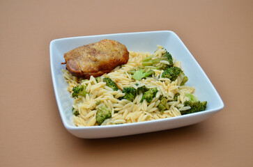 A Meal of Slow Cooked Chicken Thigh with Orzo Pasta and Broccoli Florets and Cayenne Pepper