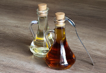 Two glass bottles with vegetable (olive, sunflower or linseed) oil on a wooden table.