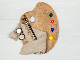 Artist's tools, a wooden palette with brushes and paints. Top view