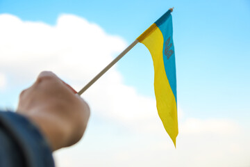 Defocus Ukraine flag. Large national symbol fluttering in blue sky. Support and help Ukraine, Independence Constitution Day, National holiday. Hand holding flag. Military. Closeup. Out of focus