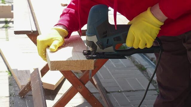 a man saws a board with an electric jigsaw close-up .hand electric saw ,the concept of working with wood