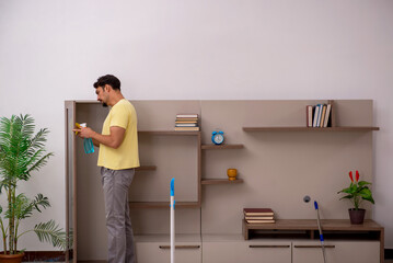 Obraz na płótnie Canvas Young man doing housework at home