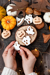 Homemade halloween holiday treats for kids. Gingerbread cookies on wooden board, decorated with pumpkins and autumn leaves. Top view