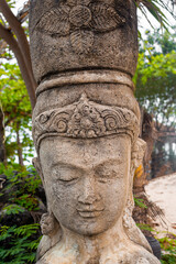 The head of a statue of a woman in an ancient national headdress in a tropical park. Travel and tourism in Asia
