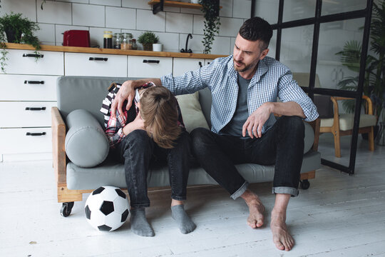 Teenager Boy With A Backpack Disappointed And Sad Because Of Football Game. Dad Supporting Him. Back To School Concept. Cute Brown Pet Dog Around