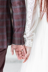 Beautiful red-hair bride in a white wedding dress and bouquet of flowers wearing pearls and a handsome groom with a red beard in a suit. Young loving couple holding hands