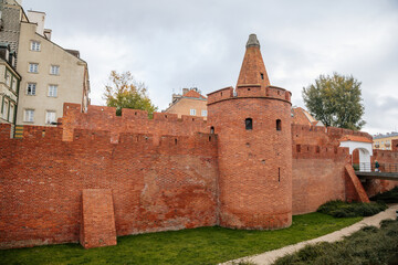 Warsaw, Poland, 13 October 2021: Barbican complex network of historic fortifications between Old and New Town, red brick fort wall with towers, major tourist attraction at sunny autumn day, city gate