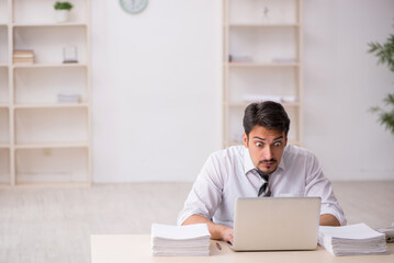 Young male employee unhappy with excessive work in the office