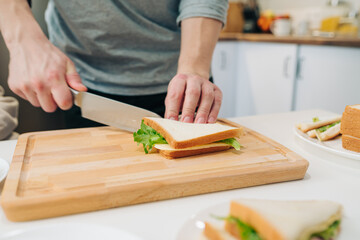Man cooking a sandwich with salad, ham and cheese. American cuisine. Cooking breakfast