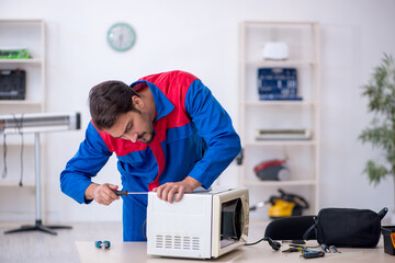 Young male repairman repairing oven at workshop