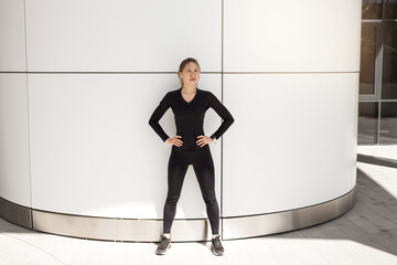 portrait of a young woman in a black tracksuit doing gymnastics