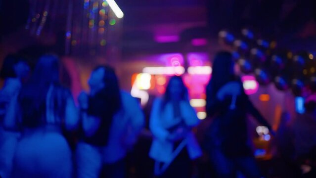 Defocused footage: Many drunk and happy women partying and dancing in a nightclub