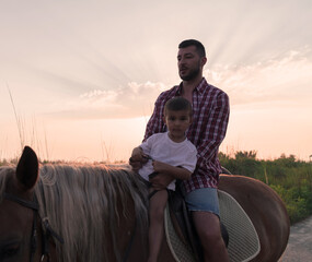 Father and son enjoy riding horses together by the sea. Selective focus 