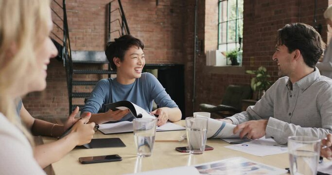 a group of businesspeople having a meeting in a modern office. diverse group of young businesspeople in a meeting, collaborate and brainstorm together. Asian businesswoman high fives a colleague