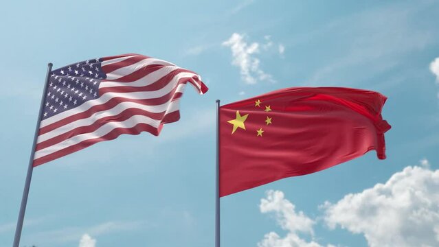 Flag of the USA and China on the flagpole flutters quickly with a strong wind in the blue sky