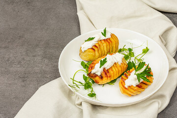 Baked accordion potatoes with fresh green pea sprouts.Traditional American food, homemade vegan diet