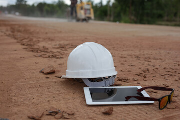 Engineer's helmet, tablet and sunglasses are placed on a concrete road construction site.