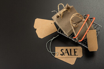 Black Friday Sale concept. Shopping basket, handmade tags, paper bags. Black background