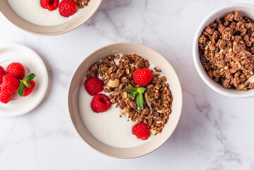 granola with yogurt and berries in a bowl on a marble background