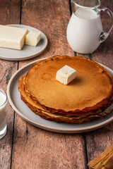 pancakes with butter and milk on a wooden background