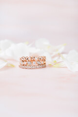 Stacked rose gold diamond ring with pink background and white flowers
