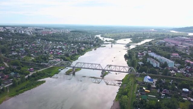Russia.The view from the drone.Clip. A big city from a height where you can see summer houses and green trees around and a big bridge over the river that spreads and you can see the white fog over the