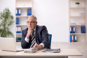 Naklejka premium Old male employee working in the office