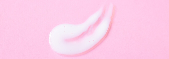 Close-up cream moisturiser smear smudge wavy texture on pink. background with copy space horizontal...