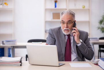 Old male employee working in the office