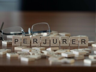 perjurer word or concept represented by wooden letter tiles on a wooden table with glasses and a book - obrazy, fototapety, plakaty