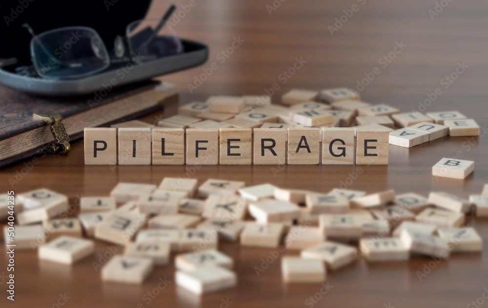 Wall mural pilferage word or concept represented by wooden letter tiles on a wooden table with glasses and a book