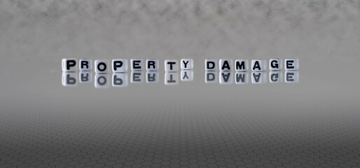 property damage word or concept represented by black and white letter cubes on a grey horizon background stretching to infinity