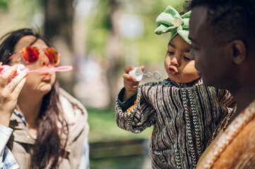 Multiracial family blowing soap bubbles in park