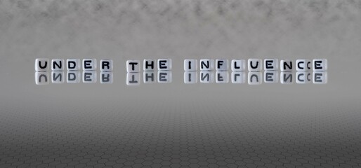 under the influence word or concept represented by black and white letter cubes on a grey horizon...