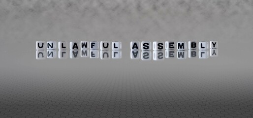 unlawful assembly word or concept represented by black and white letter cubes on a grey horizon background stretching to infinity