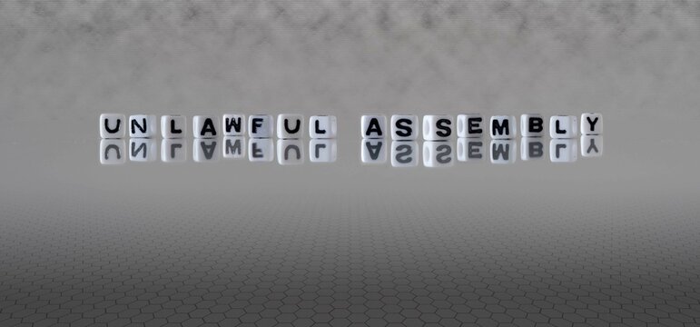 Unlawful Assembly Word Or Concept Represented By Black And White Letter Cubes On A Grey Horizon Background Stretching To Infinity