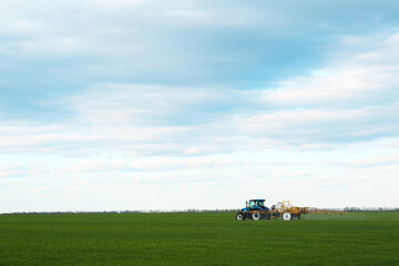 Tractor spraying pesticide in field on spring day. Agricultural industry