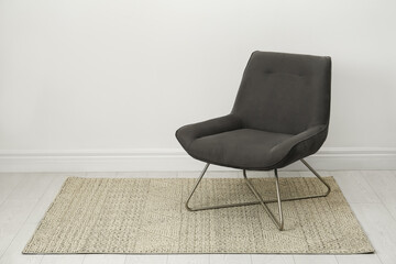 Stylish grey armchair near white wall indoors. Space for text