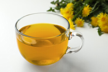 Delicious fresh tea and beautiful dandelion flowers on white background, closeup